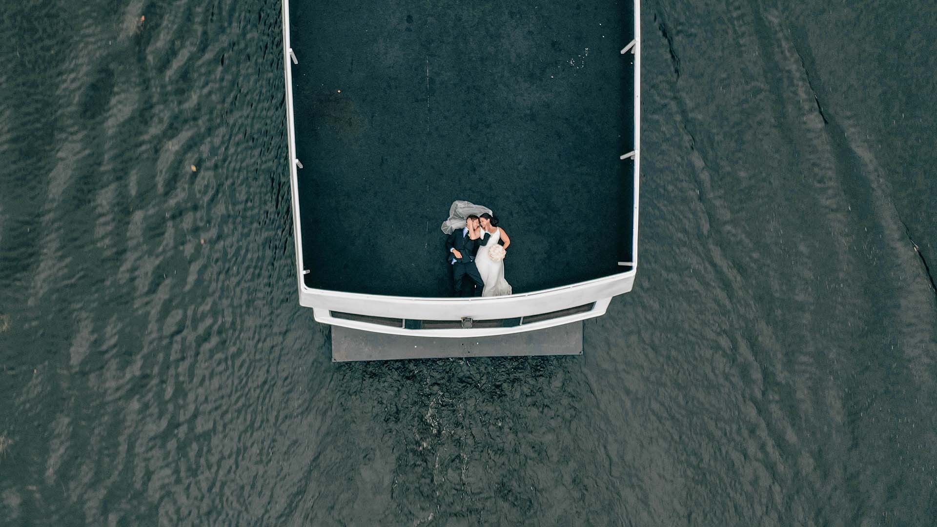 Elopement photographer - a bride and groom lay on the deck of a boat at their elopement. Photographed by drone