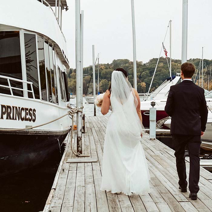 Elopement photographer - a newlywed couple walk along a pier after being married on a boat