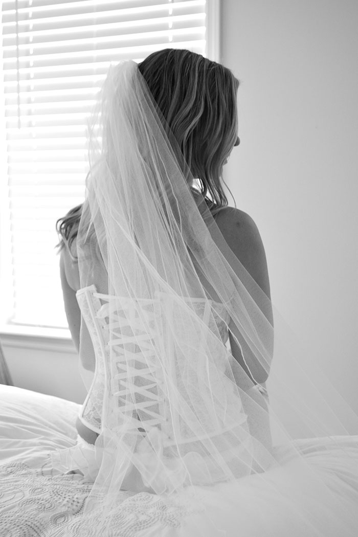 Boudoir photographer - a bride sits on her bed