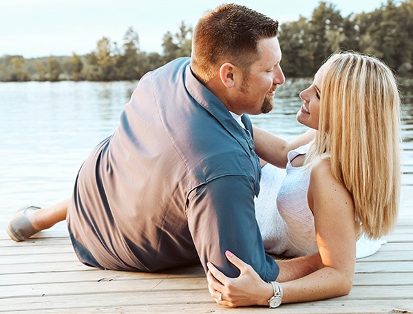 Engagement photographs - a newly engaged couple lay on a pier overlooking a lake