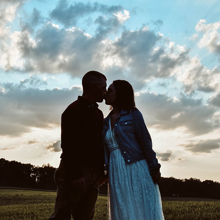 Engagement photographer - a man and woman kiss outside at dusk