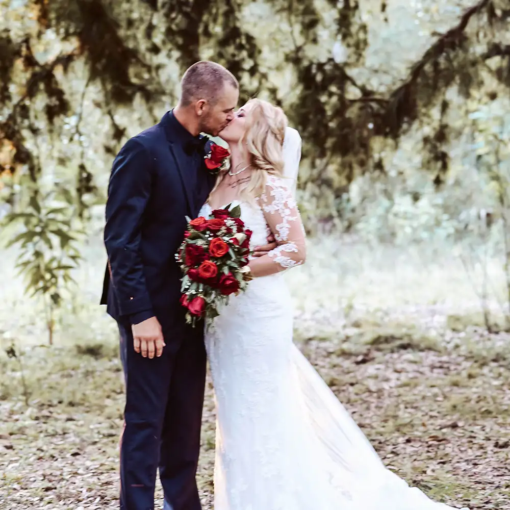 Wedding photographer - a newlywed couple kiss near a tree