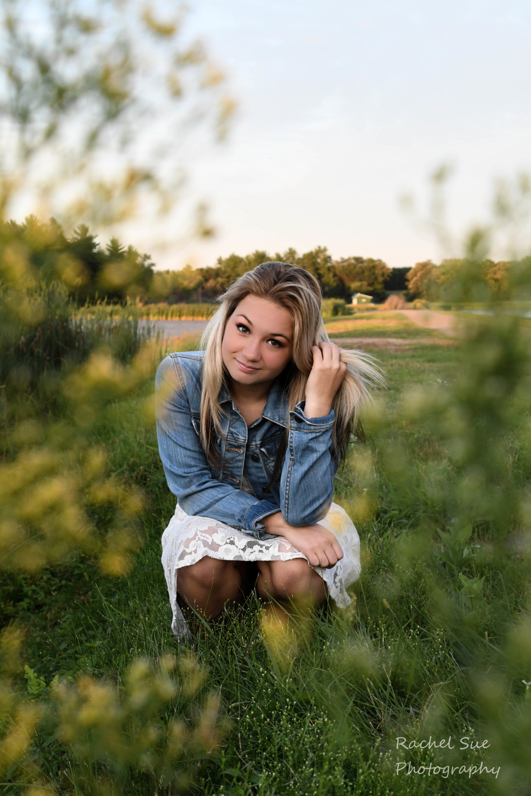 Branding photography - a young woman crouches in the grass