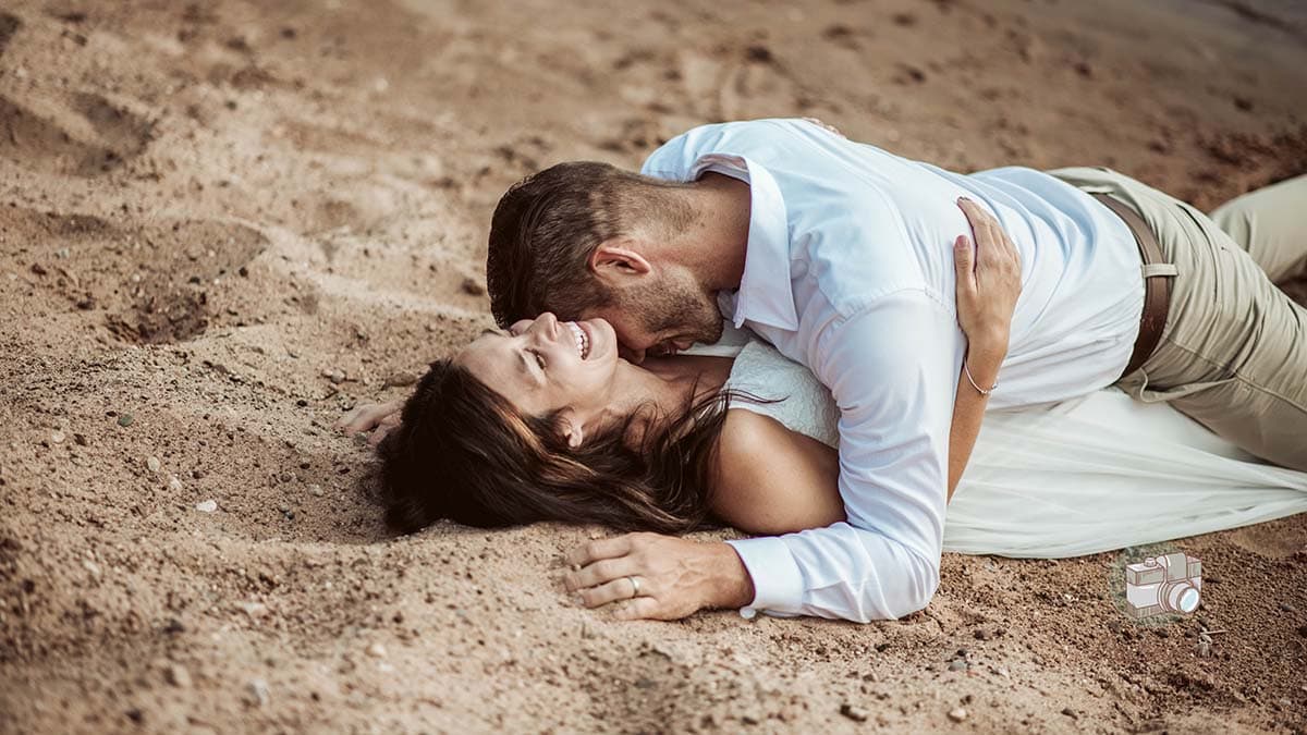 A couple lie on the beach together after their elopement.