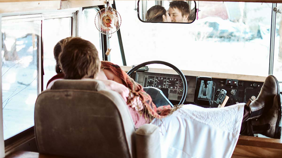 A bride and groom kiss on the seat of their campervan, after eloping.