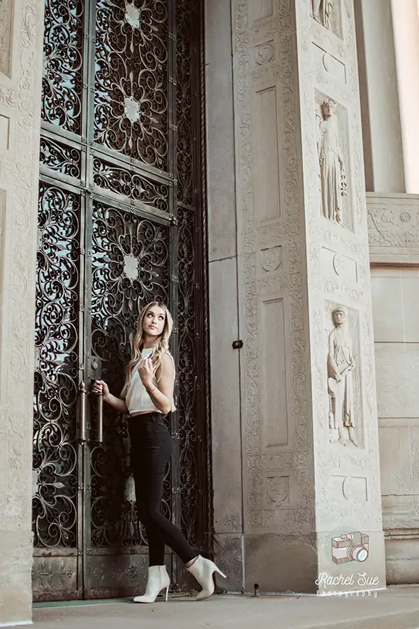 a girl poses in front of a door for her senior portrait