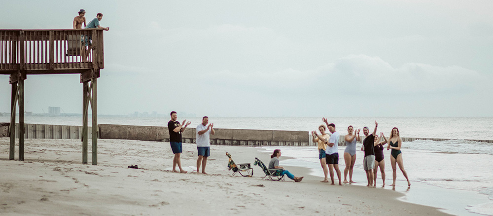 A group of beach goers cheer for the married couple at an elopement. Photographed at Murrells Inlet, South Carolina