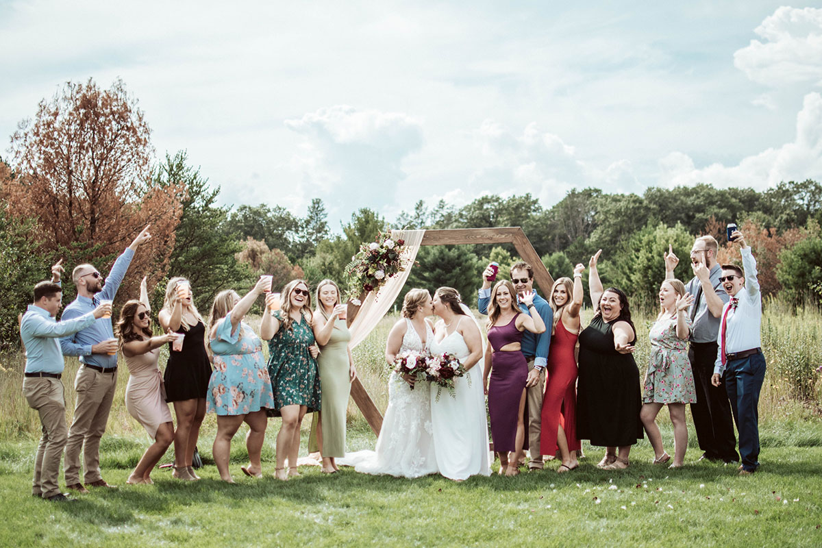 The guests celebrate the intimate wedding in Wisconsin, while the two brides kiss.