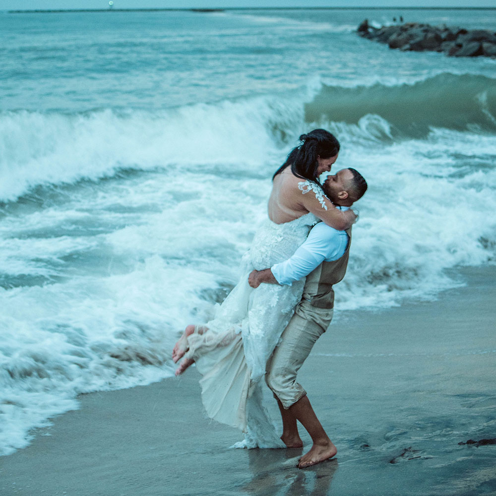 the groom carries the bride on the beach at their elopement
