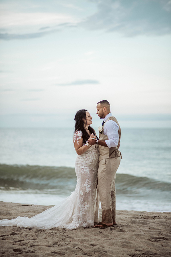 a couple look at each other on the beach after their wedding