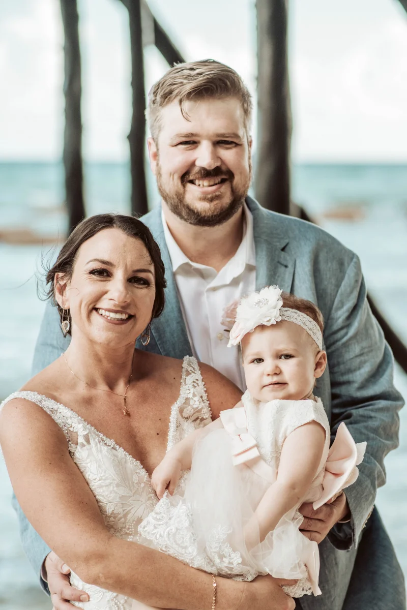 Newly married couple hold their baby daughter