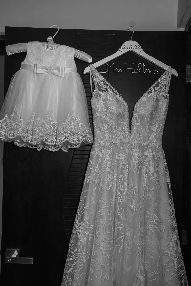 The bride's dress hangs next to a baby's dress.