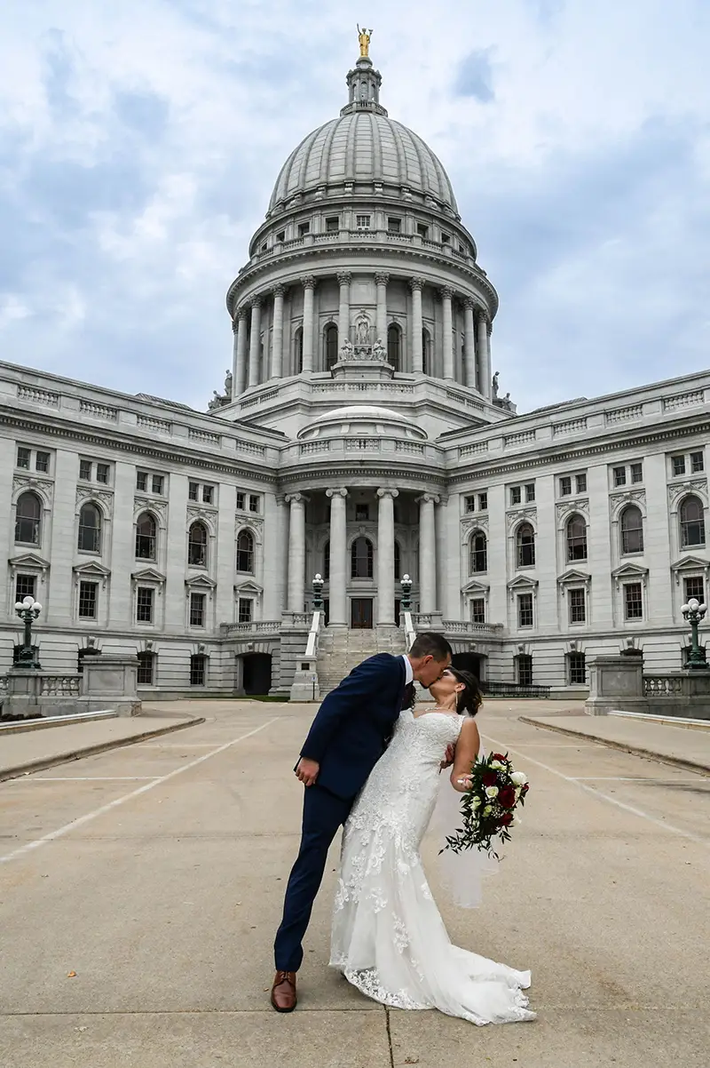 A bride and groom kiss outside of the Wisconsin State Capitol