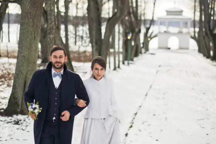 A newlywed couple walking along a snowy path in Canada
