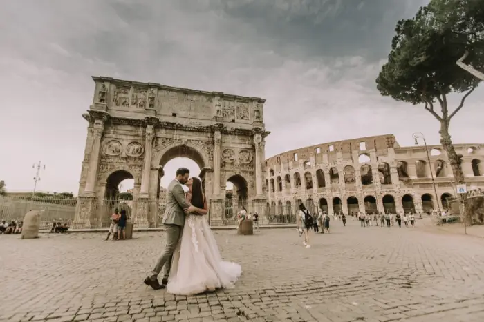 A newly married couple who have eloped to Rome. Constantine's Arch and the Colosseum are visible in the background