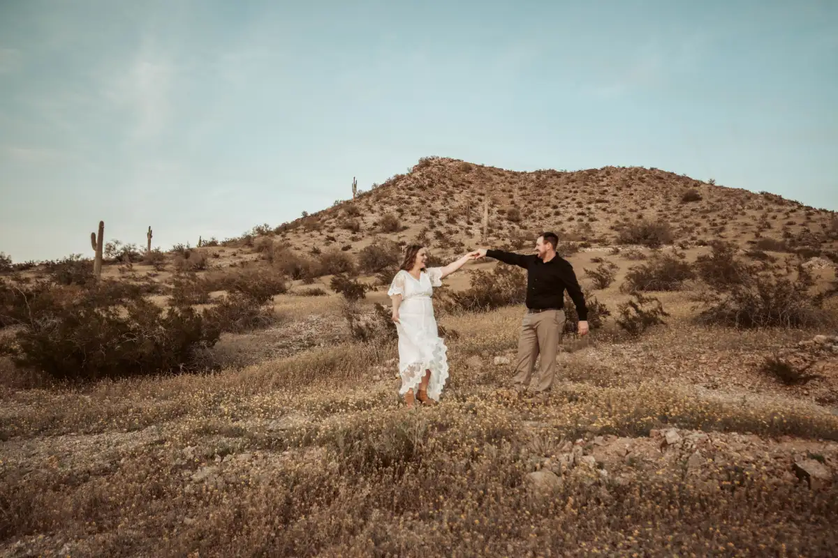 A newly wed couple holding hands at their desert elopement.