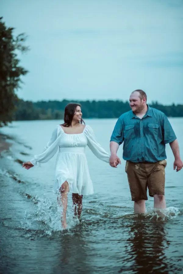 A couple walk though water at the beach during their elopement