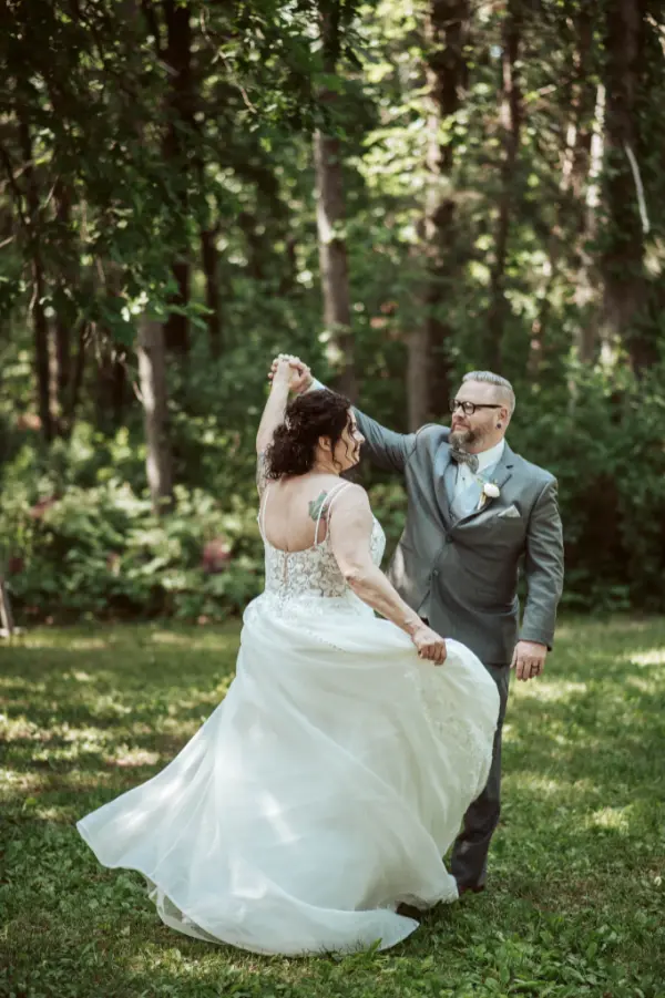 A newlywed couple dancing in a woodland setting